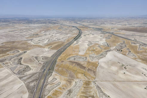 Aerial view of the highway crossing the desert valley near Monegros desert, Zaragoza, Spain. - AAEF20541