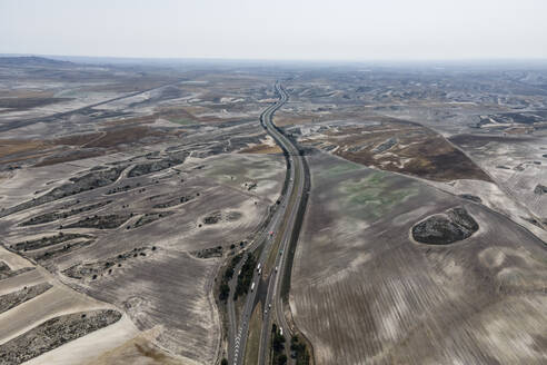 Aerial view of the highway crossing the desert valley near Monegros desert, Zaragoza, Spain. - AAEF20542