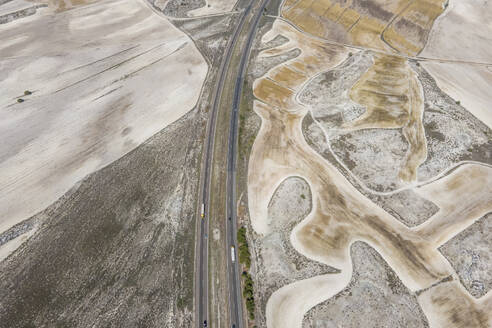 Aerial view of the highway crossing the desert valley near Monegros desert, Zaragoza, Spain. - AAEF20544