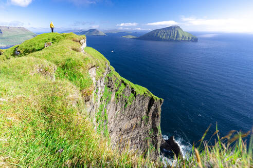 Eine Person bewundert die Aussicht auf den Klippen über dem Meer, Nordradalur, Insel Streymoy, Färöer Inseln, Dänemark, Europa - RHPLF26091