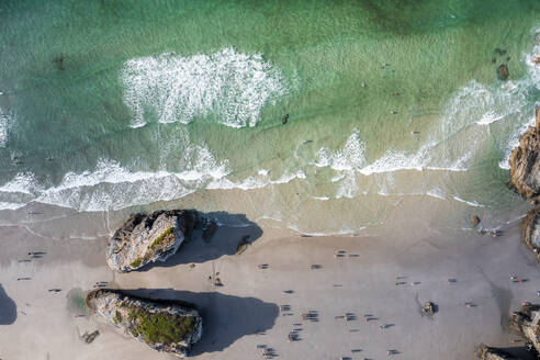 Aerial view of people on the beach with rocks along the shoreline near Ribadeo, Lugo, Spain. - AAEF20664