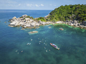 Aerial view of group snorkeling and swimming in transparent sea in shark bay on Ko Tao island, Thailand. - AAEF20850