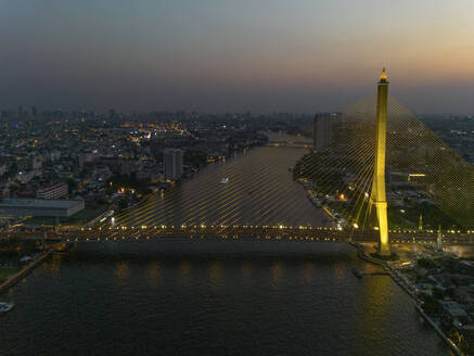 Aerial view of The Rama VIII Bridge, a cable-stayed bridge crossing the Chao Phraya River at night in Bangkok, Thailand. - AAEF20866