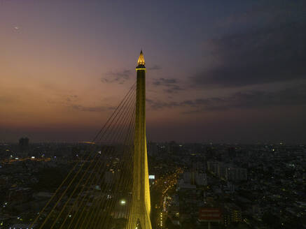 Aerial view of The Rama VIII Bridge, a cable-stayed bridge crossing the Chao Phraya River at night in Bangkok, Thailand. - AAEF20867