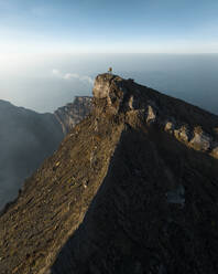 Aerial view of a person on top of Mount Agung at sunset, a volcano on Bali Island, Indonesia. - AAEF20958