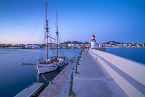 View of harbour lighthouse and sailing ship at dusk, UNESCO World Heritage Site, Ibiza Town, Eivissa, Balearic Islands, Spain, Mediterranean, Europe - RHPLF26325