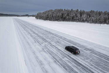 Car traveling on ice track on a frozen lake in the snow covered landscape, Jokkmokk, Norrbotten, Lapland, Sweden, Scaninavia, Europe - RHPLF26518