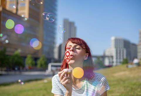 Frau beim Blasen von Seifenblasen an einem sonnigen Tag - BFRF02430