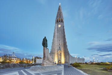 A dusk view of the spire of Hallgrimskirkja Church, fronted by a statue of Leifur Eriksson, founder of Iceland, in central Reykjavik, Iceland, Polar Regions - RHPLF26700