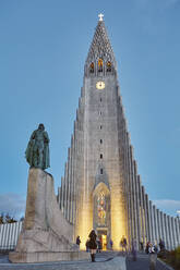 A dusk view of the spire of Hallgrimskirkja Church, fronted by a statue of Leifur Eriksson, founder of Iceland, in central Reykjavik, Iceland, Polar Regions - RHPLF26701