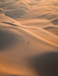 Aerial view of a person walking among the sand dunes in the desert of Dubai at sunset, United Arab Emirates. - AAEF21013