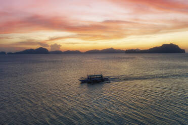 Aerial view of a passenger boats sailing at sunset across El Nido Bay, Palawan, Philippines. - AAEF21019