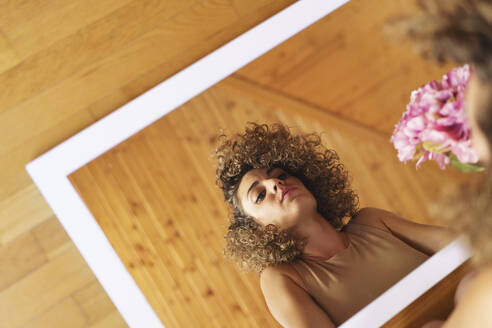 Reflexion der Frau auf Spiegel mit Blumenstrauß zu Hause - JSMF02866