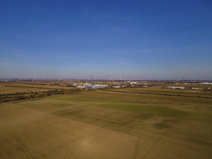 Aerial drone view of agricultural fields on an early spring day with buildings and wind turbines in the distance, Gerasdorf, Lower Austria, Austria. - AAEF21396