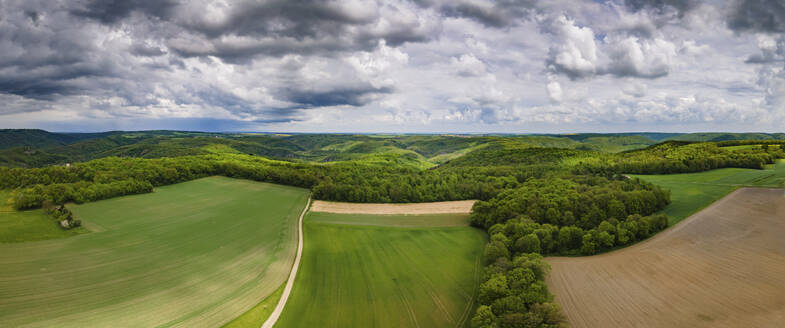 Aerial drone panoramic view in summer of Thayatal National Park on a cloudy day with fields in the foreground and the Czech Republic in the distance, Hardegg, Lower Austria, Austria. - AAEF21404