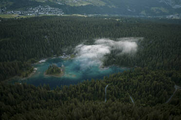 Aerial drone view a clear water lake covered in fog, Eibsee, Flims, Graubunden, Switzerland. - AAEF21568