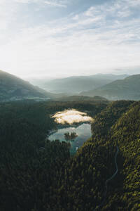 Aerial drone view a clear water lake covered in fog, Eibsee, Flims, Graubunden, Switzerland. - AAEF21571