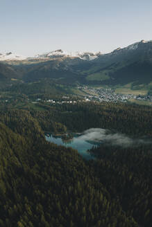 Aerial drone view a clear water lake covered in fog, Eibsee, Flims, Graubunden, Switzerland. - AAEF21575