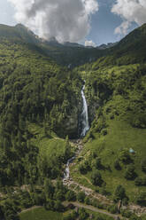 Aerial drone view of the waterfall Cascata La Froda in Sonogno surrounded by lush green grass and trees, Verzasca, Switzerland. - AAEF21589