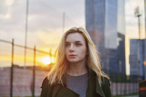 Nachdenkliche blonde Frau beim Spaziergang in der Stadt bei Sonnenuntergang - AZF00560