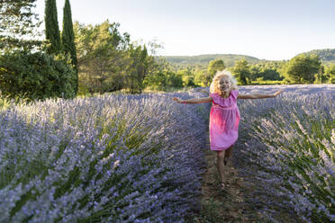 Girl running amidst lavender plants in field - SVKF01589