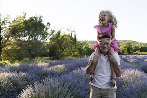 Fröhliches Mädchen bedeckt die Augen des Vaters im Lavendelfeld - SVKF01591
