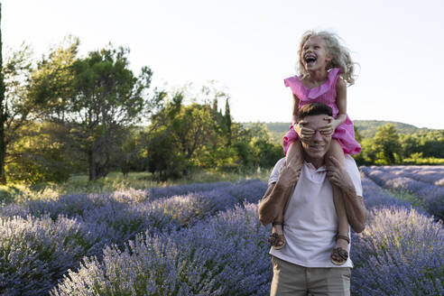 Cheerful girl covering eyes of father in lavender field - SVKF01591