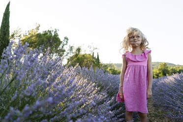 Happy girl making face and standing in lavender field - SVKF01593