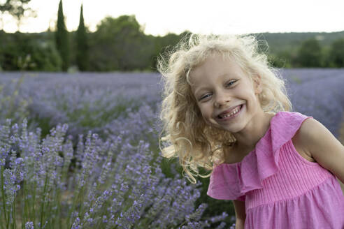 Glückliches blondes Mädchen vor einem Lavendelfeld - SVKF01595