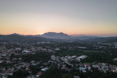 Aerial view of a valley with residential houses in Irpinia at sunset with Mount Vergine in background, Avellino, Italy. - AAEF21630