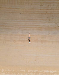 Aerial view of a person along the shoreline with a book at Baia de Sao Martinho do Porto, Leiria, Portugal. - AAEF21686