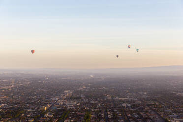 Aerial view of hot air balloons at sunset flying over Melbourne residential district, Victoria, Australia. - AAEF21844