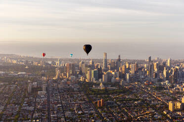 Aerial view of hot air balloons at sunset flying over Melbourne downtown district, Victoria, Australia. - AAEF21845