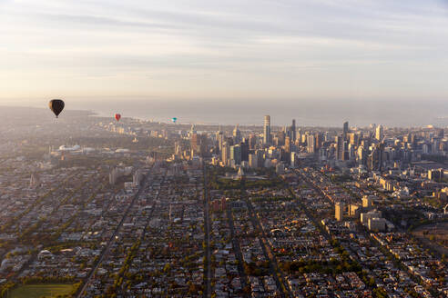 Aerial view of hot air balloons at sunset flying over Melbourne downtown district, Victoria, Australia. - AAEF21846