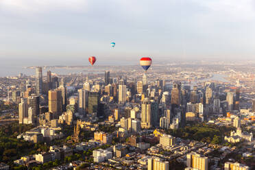 Aerial view of hot air balloons at sunset flying over Melbourne downtown district, Victoria, Australia. - AAEF21847