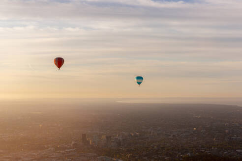 Aerial view of hot air balloons at sunset flying over Melbourne downtown district, Victoria, Australia. - AAEF21848