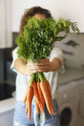 Frau hält ein Bündel Karotten in der Küche - JSMF02879