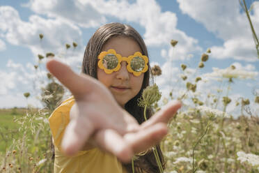 Girl with flower sunglasses gesturing in field - OSF01969