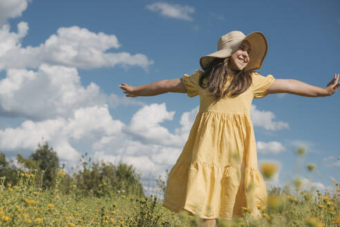 Glückliches Mädchen mit ausgestreckten Armen auf einem Feld an einem sonnigen Tag - OSF01973