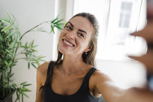 Happy woman taking selfie in apartment - DCRF01667