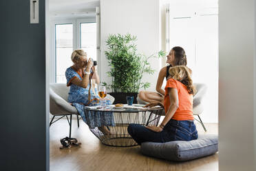 Happy woman photographing friends in apartment - DCRF01690