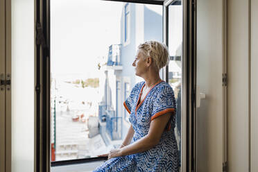 Thoughtful mature woman looking through window - DCRF01710