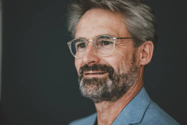 Kontemplativer Geschäftsmann mit Brille vor türkisfarbenem Hintergrund - JOSEF20503