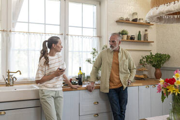 Couple talking to each other standing in kitchen at home - VPIF08369