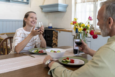 Happy woman having food and drink with man at dining table at home - VPIF08372