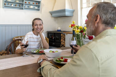 Mature couple having dinner sitting at dining table at home - VPIF08373