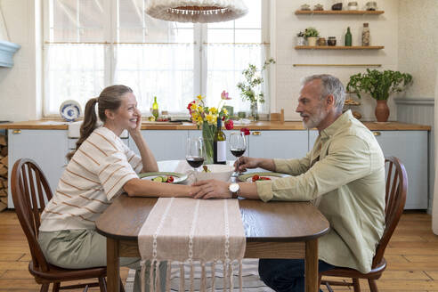 Romantic couple enjoying wine sitting at dining table - VPIF08374