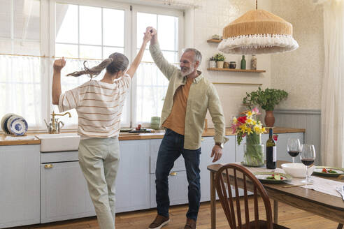 Happy mature couple dancing in kitchen at home - VPIF08377