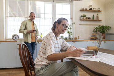 Mature woman preparing bills with man at home - VPIF08380