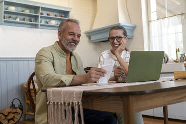 Happy couple examining financial bills at home - VPIF08384